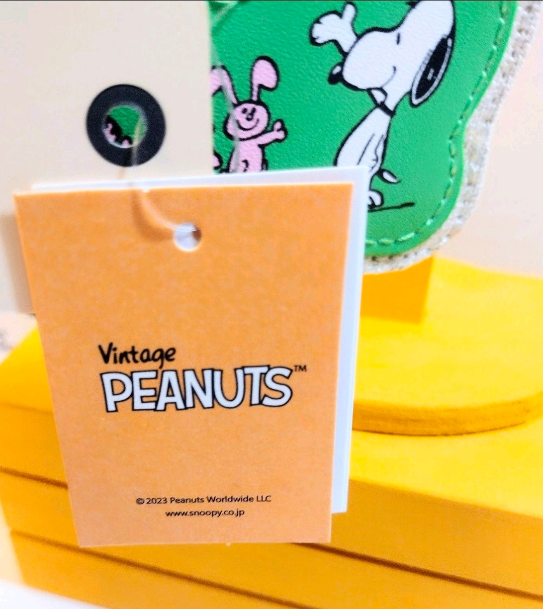 Orange retail tag attached to Snoopy green keychain with beige fabric