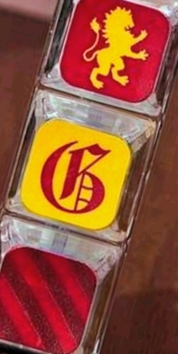 Stacked keycap fidget charm with red lion and yellow crest emblems, clear plastic