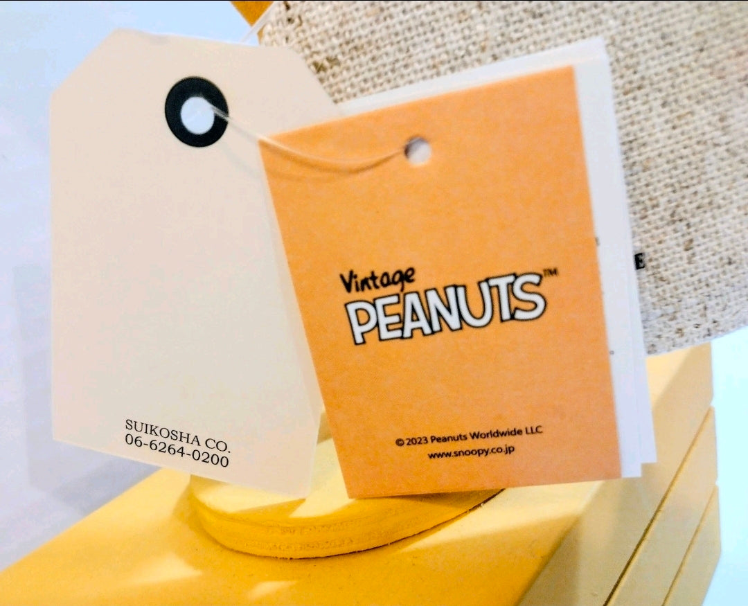 Accommode and Vintage Peanuts hang tags attached to a grey keychain pouch