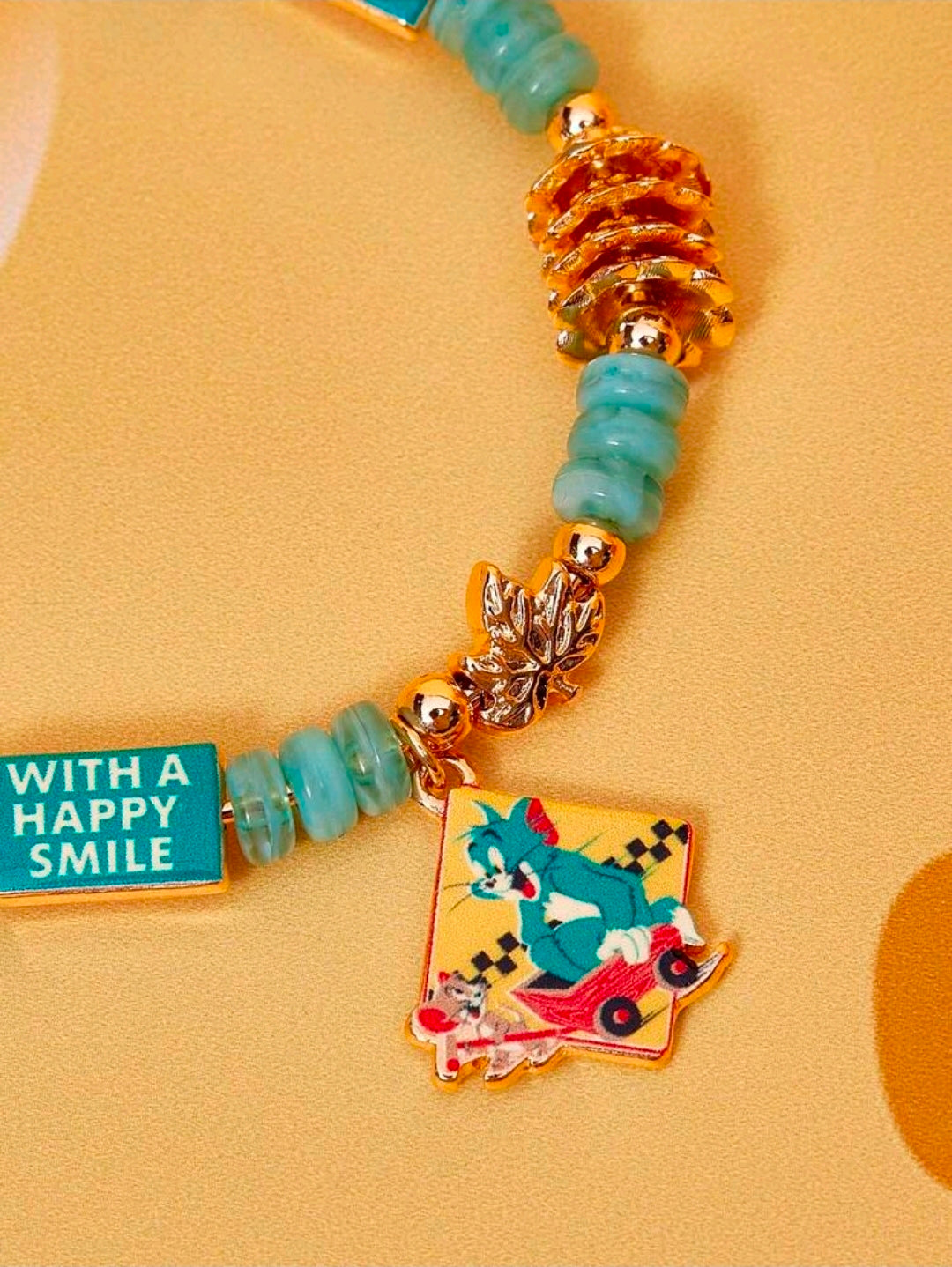 Gold-tone teal bead charm bangle bracelet with taxi cab, travel bottle, and cartoon charm
