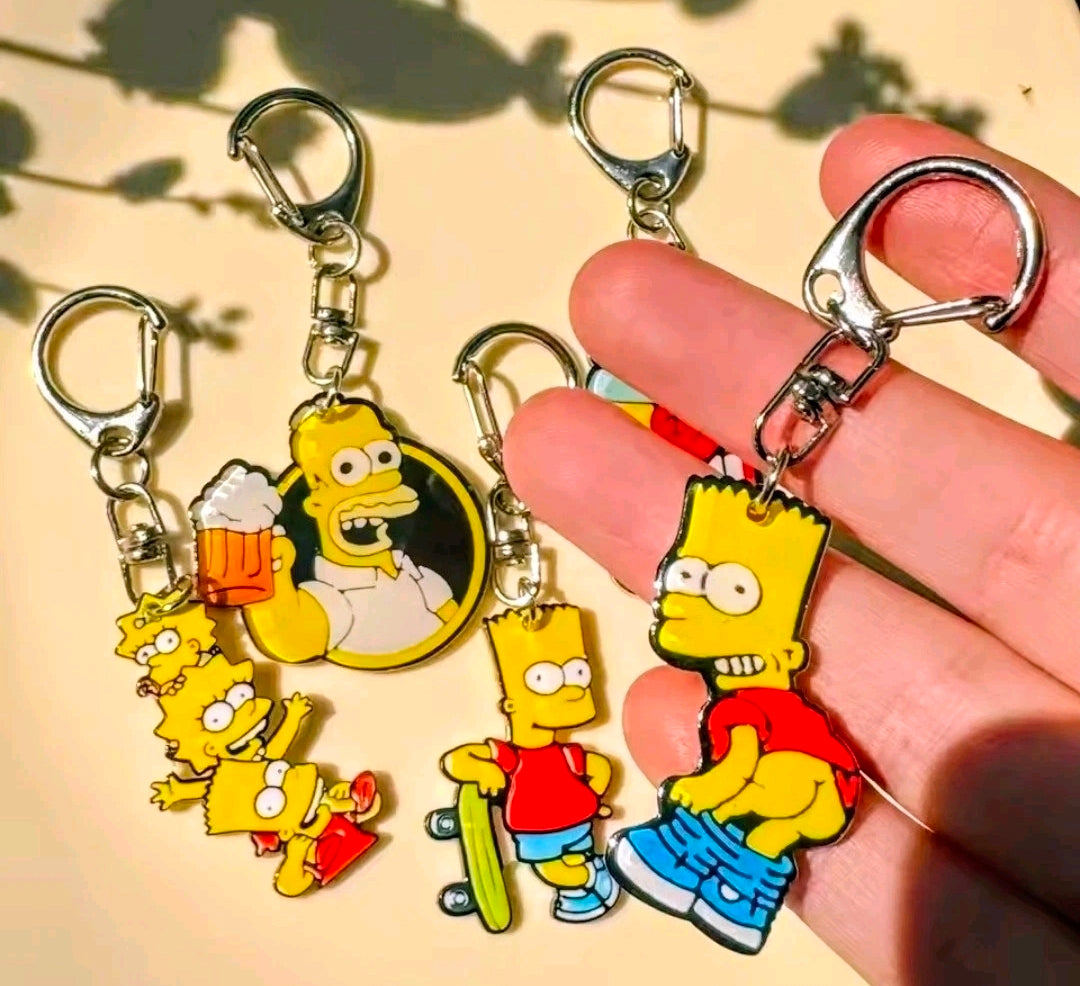 Simpsons acrylic keychain set in hand, showing Bart, Homer, and Duff beer can charms with rings