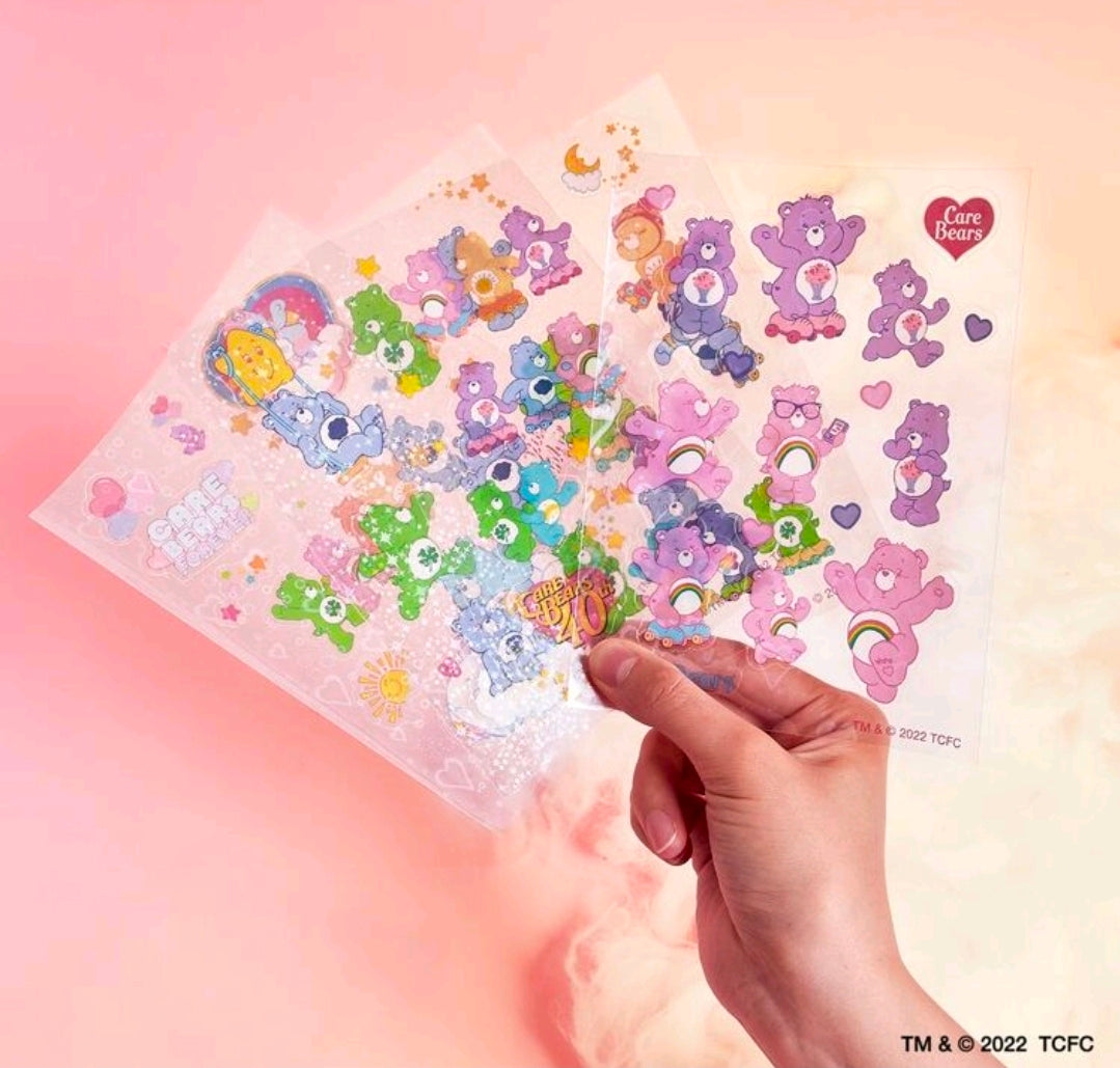 Hand holding a clear holographic sticker sheet with colorful bear shapes and heart motifs
