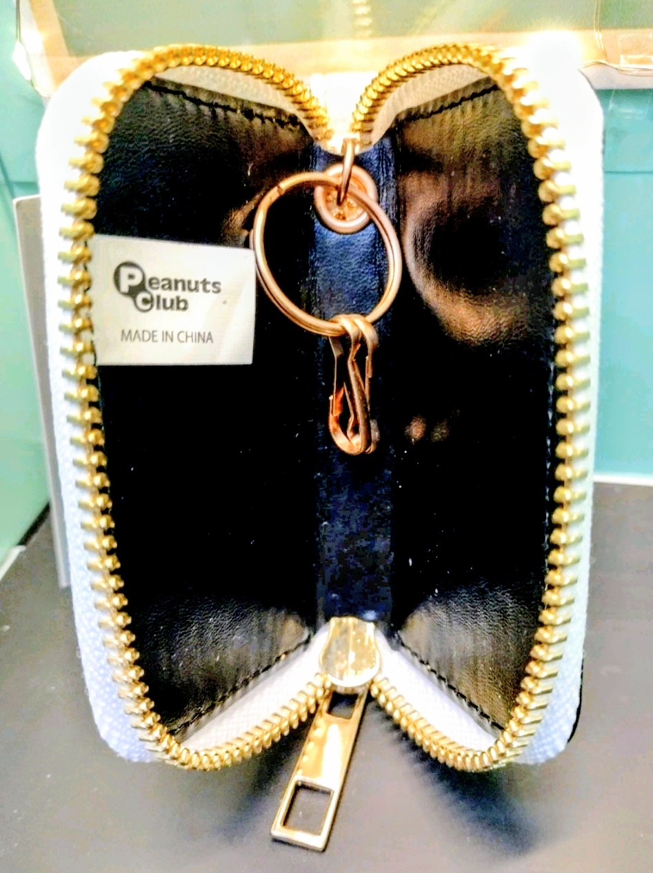Smart key case with gold zipper, black interior, and attached metal key ring