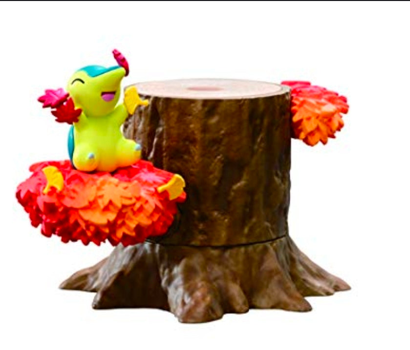 Green mouse-like figure in orange leaf skirt pose on a brown tree-stump base