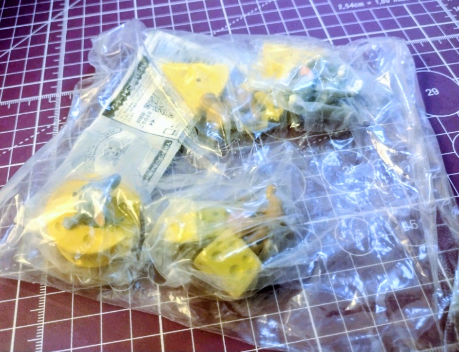 Sealed gashapon figure set in clear plastic bag on a grid cutting mat