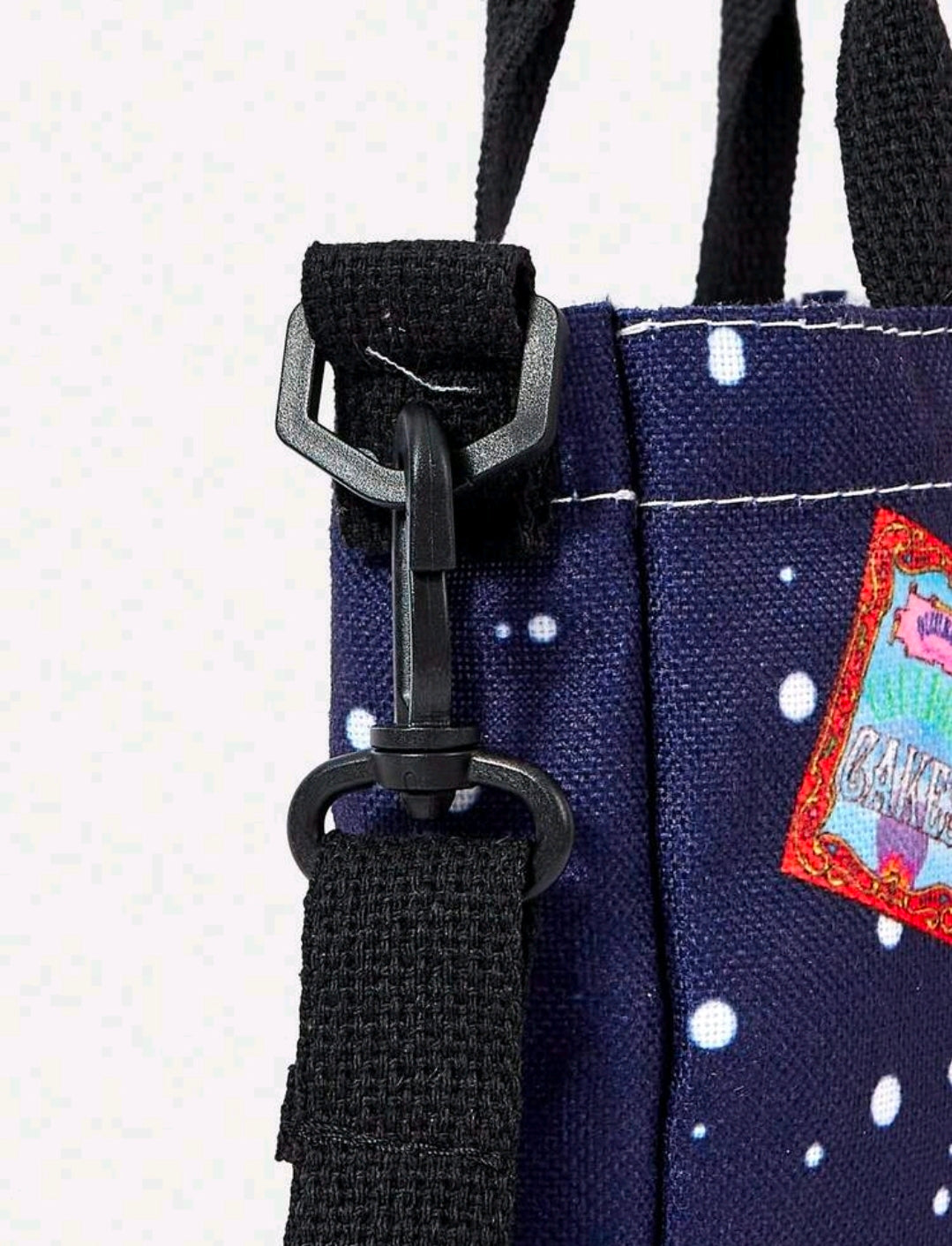 Navy canvas tote bag zipper and black shoulder strap with white polka dots and patch