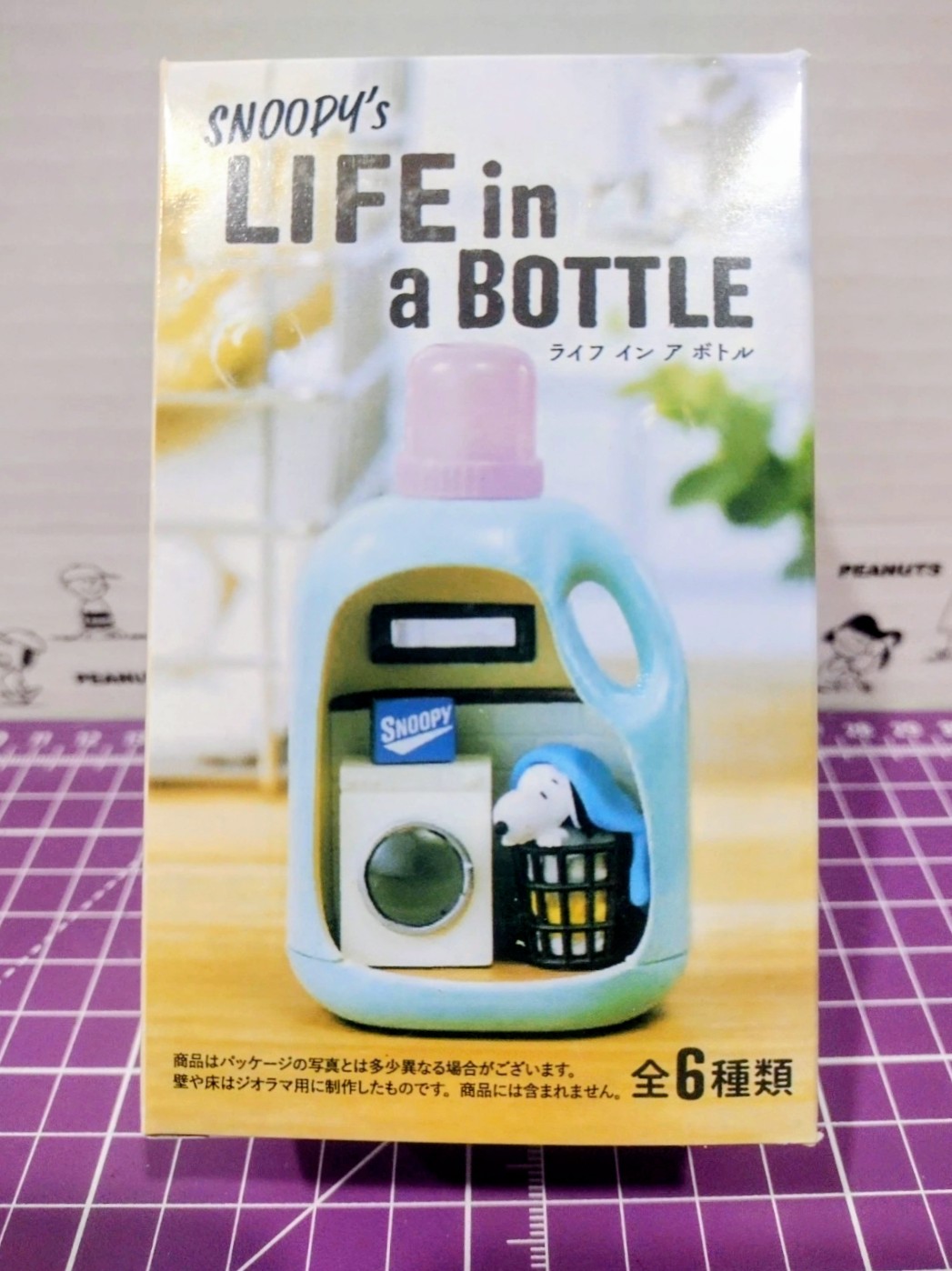 Snoopy Life in a Bottle toy figure box showing light blue detergent bottle with purple cap