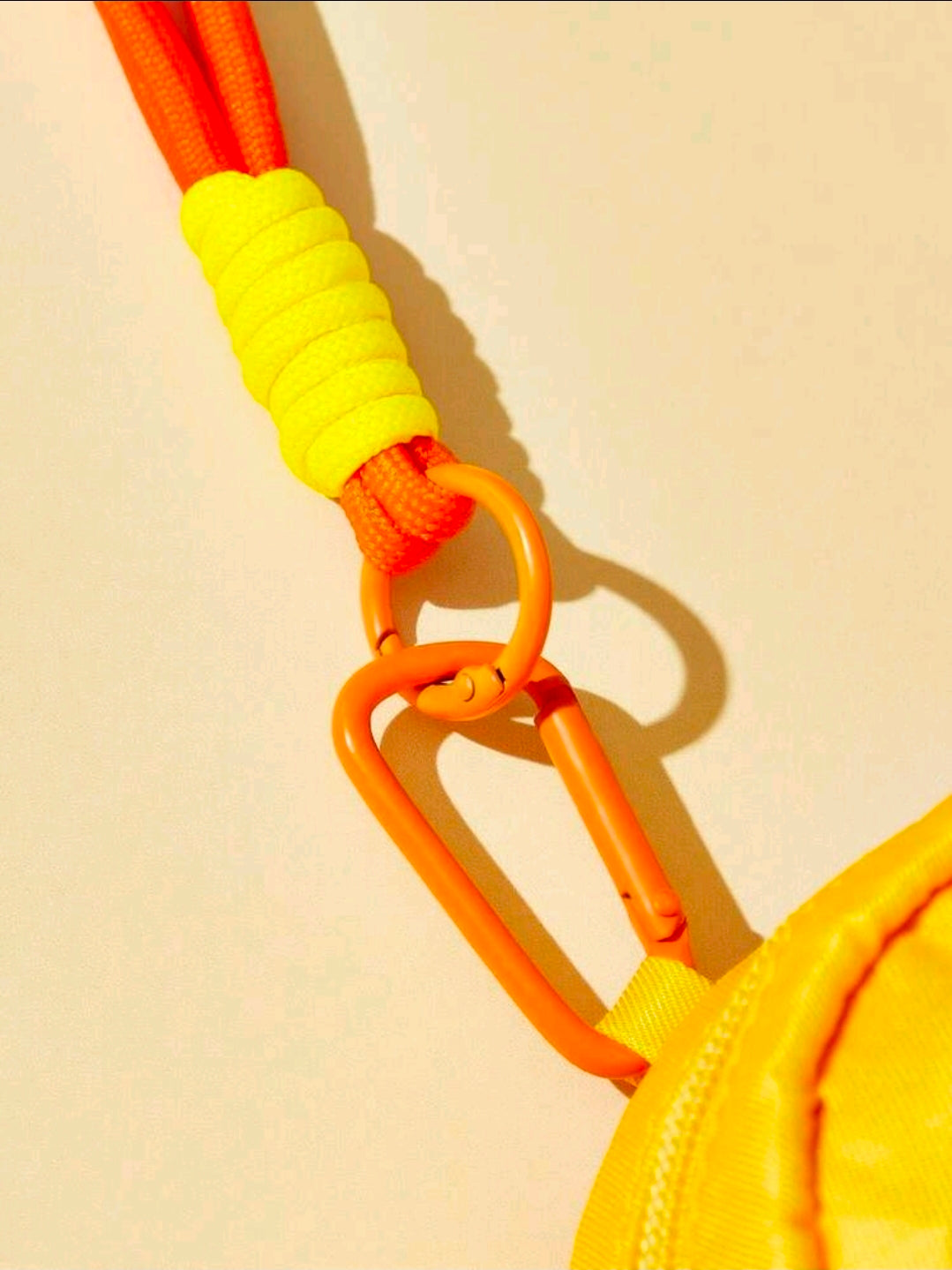 Yellow pouch with orange zipper pull, ribbed strap and orange carabiner ring
