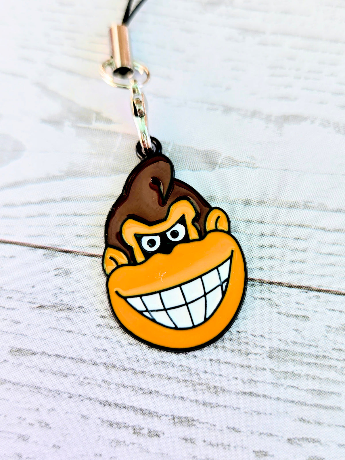 Black cord phone charm wrist strap with Donkey Kong grin enamel face charm
