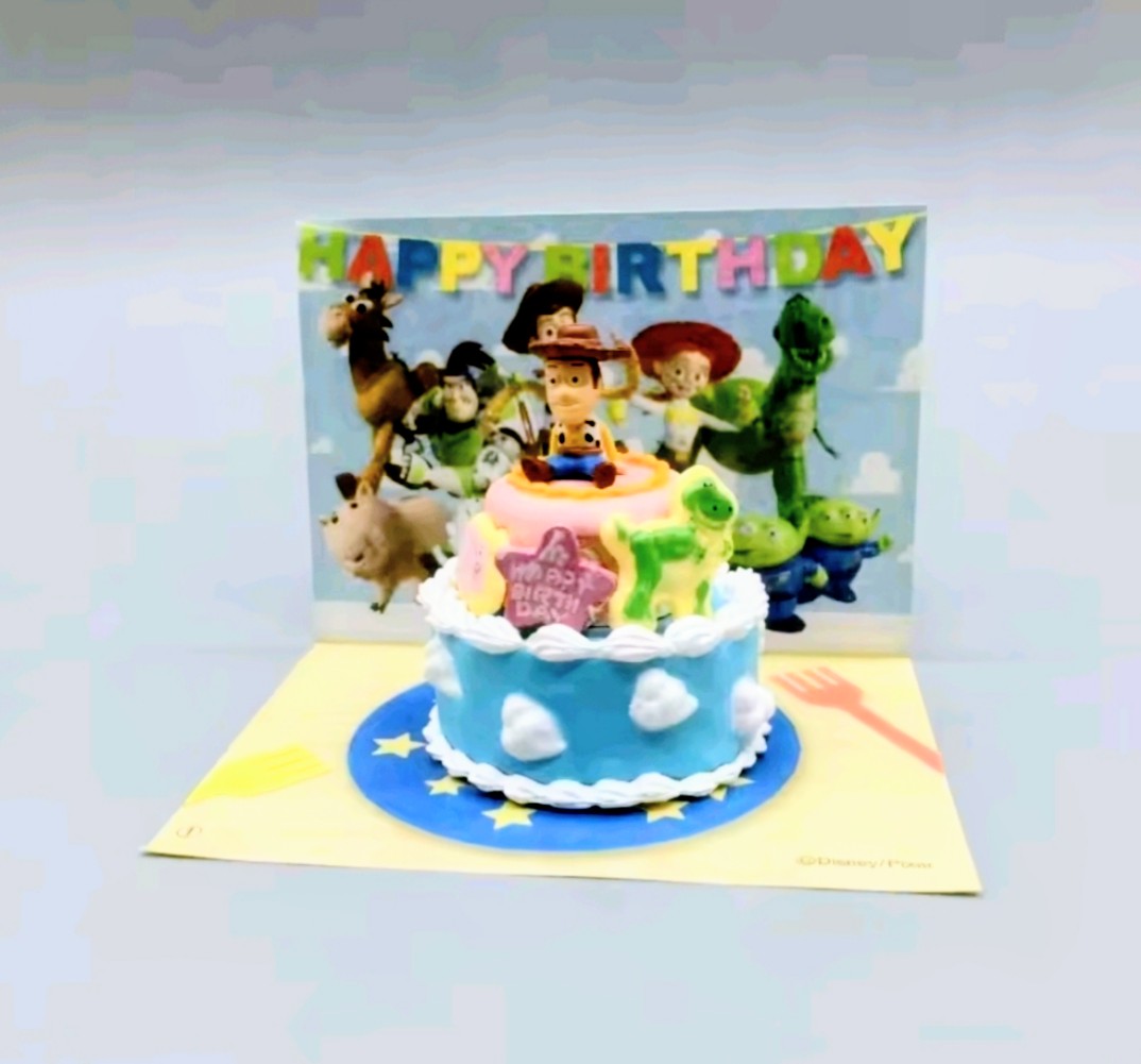 Mini birthday cake toy on display base featuring Woody figure and “Happy Birthday” top banner