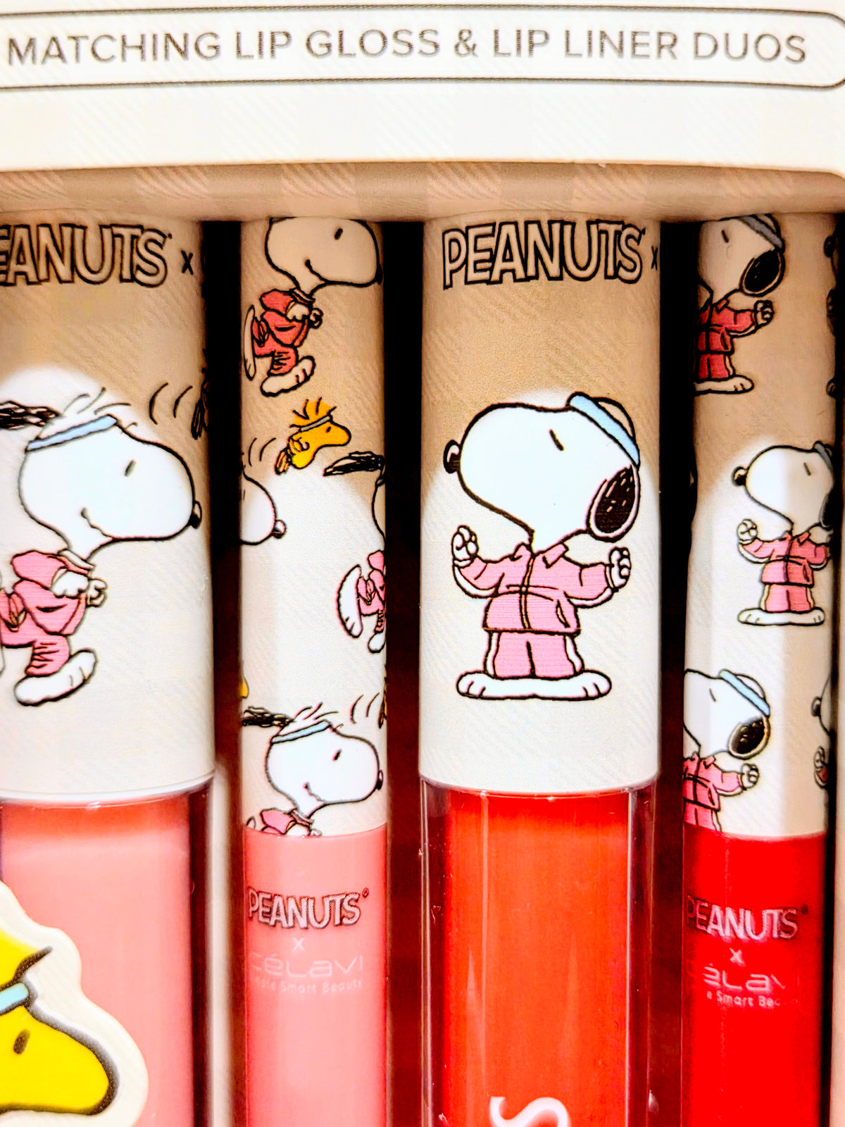 Set of matching lip gloss and lip liner tubes with Snoopy character illustrations.