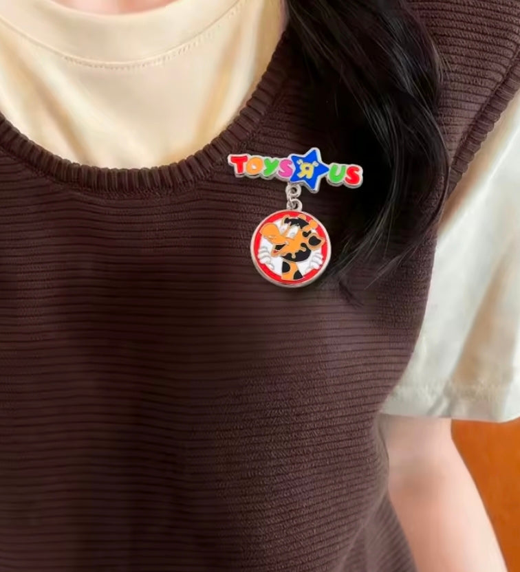 Enamel dangle charm pin worn on dark knit top