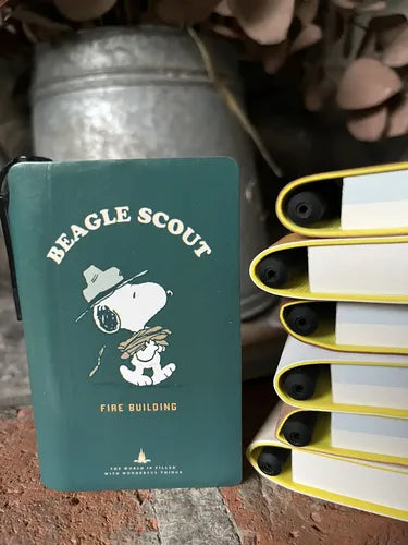 Dark teal Beagle Scout pocket field notebook with Fire Building cover art and yellow pen