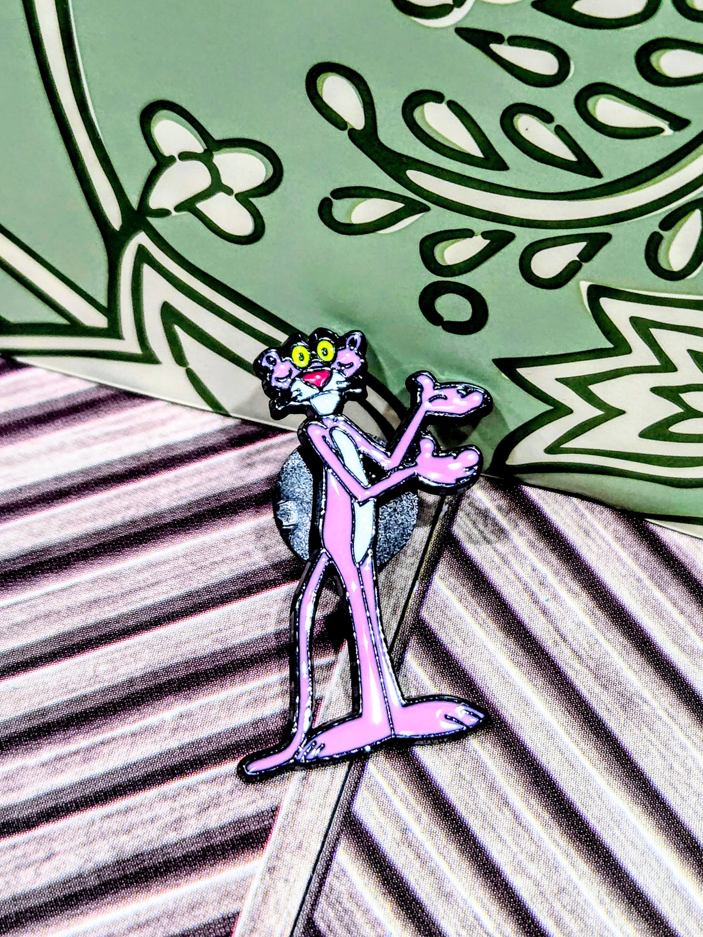 Enamel cat character pin in pink and black, standing with one hand raised