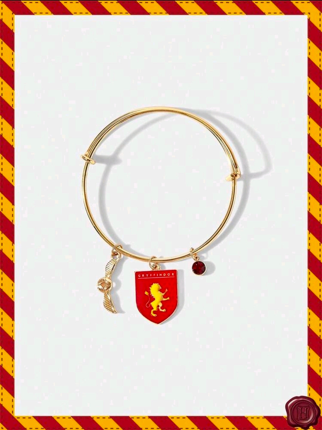 Gold-tone charm bangle with Gryffindor red shield charm and winged gold charm
