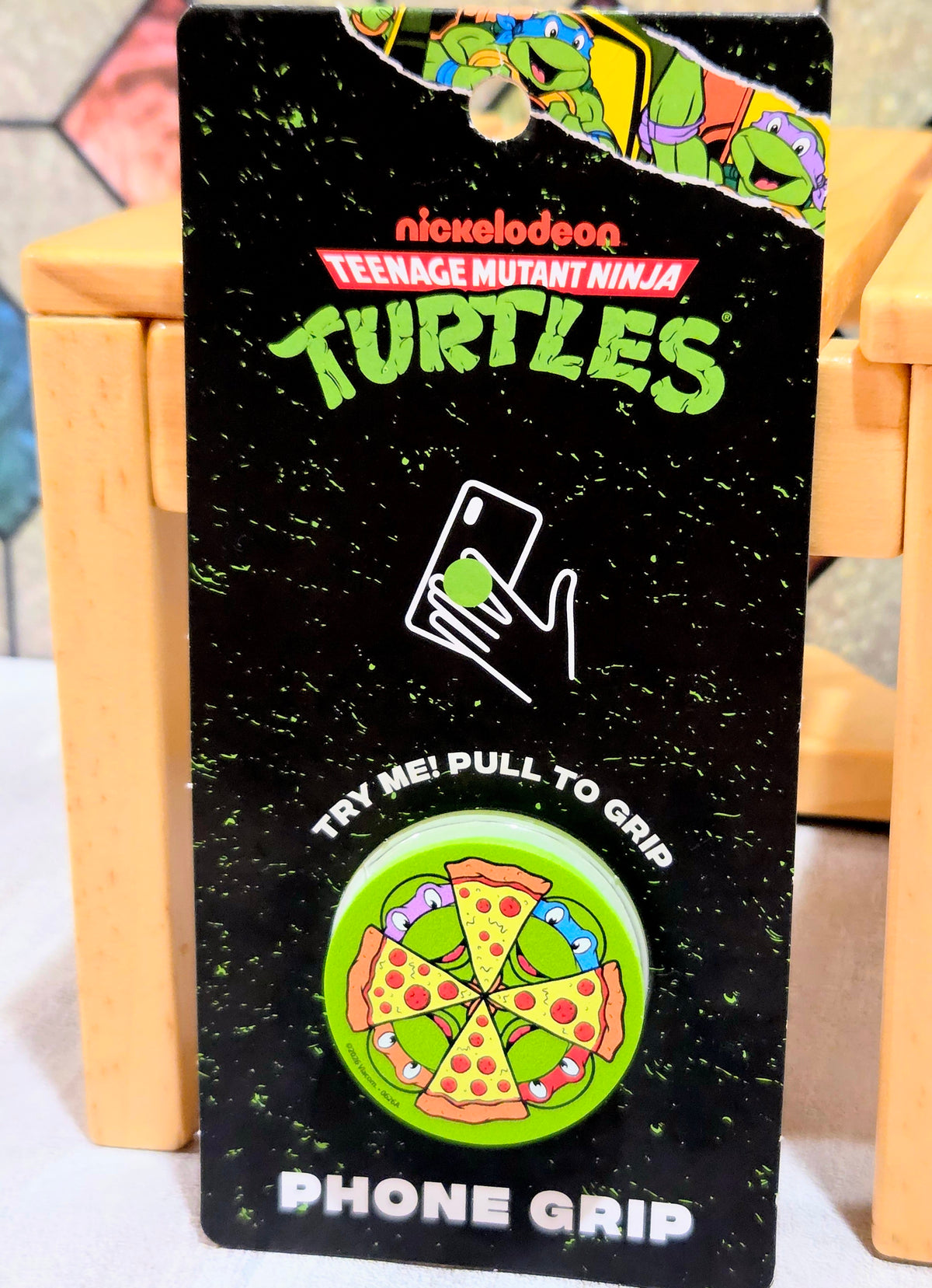 TMNT phone grip card with pizza wheel graphic and pull-to-grip icon
