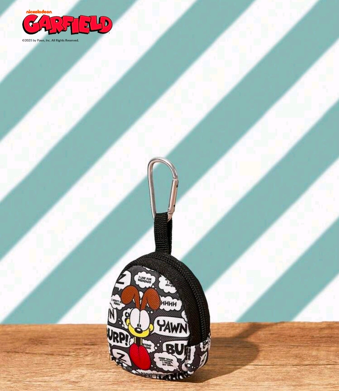 Round black comic-print pouch keychain with metal carabiner on display
