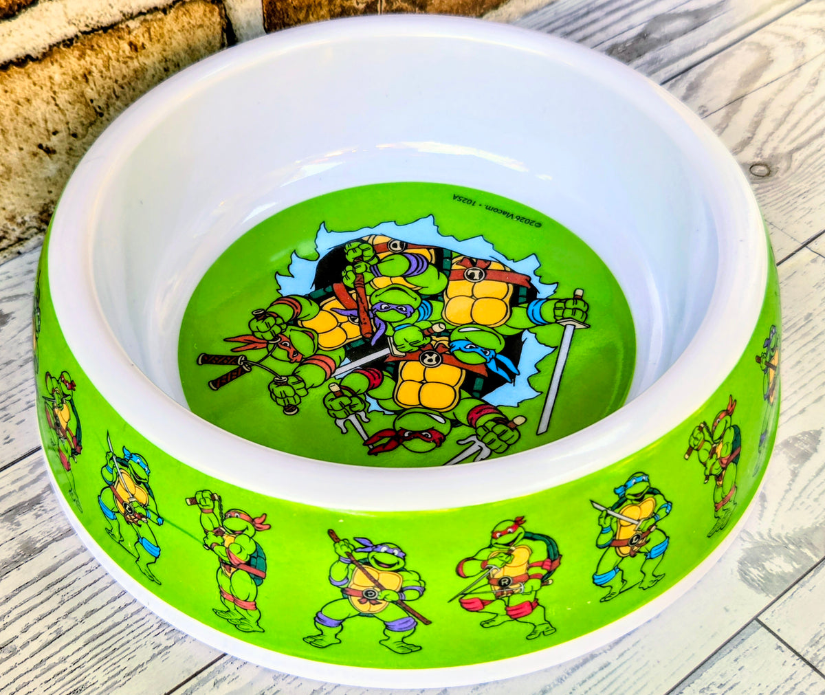 White-and-neon green pet bowl with TMNT turtle artwork on the rim and center