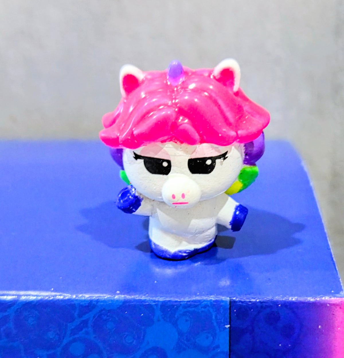 Pink ponytail squish head with black eyes, white face and blue base