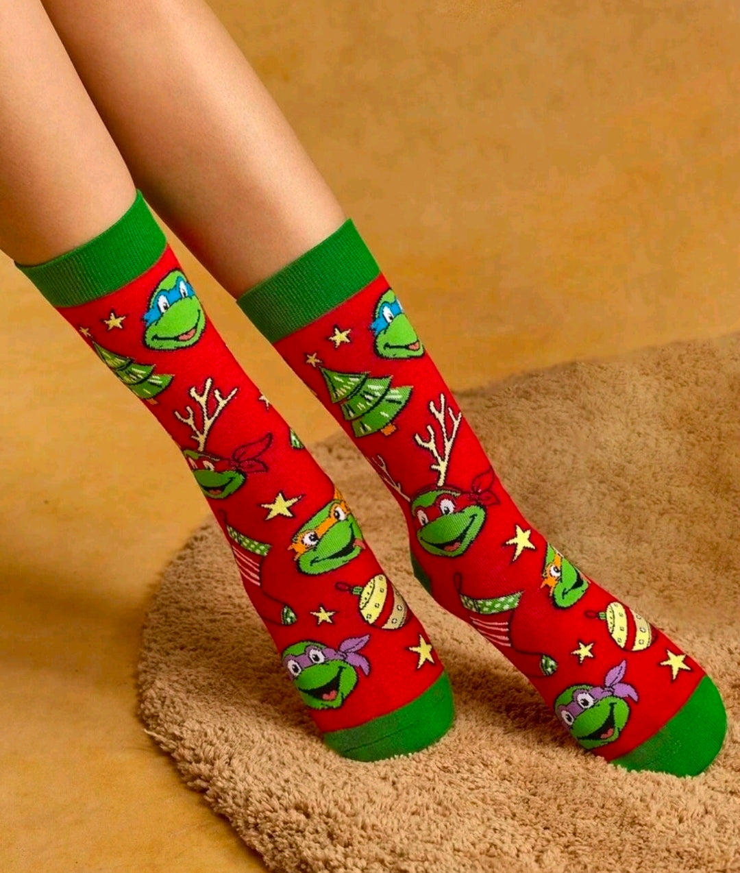 Pair of red crew socks with green cuffs and cartoon turtle Christmas pattern on legs