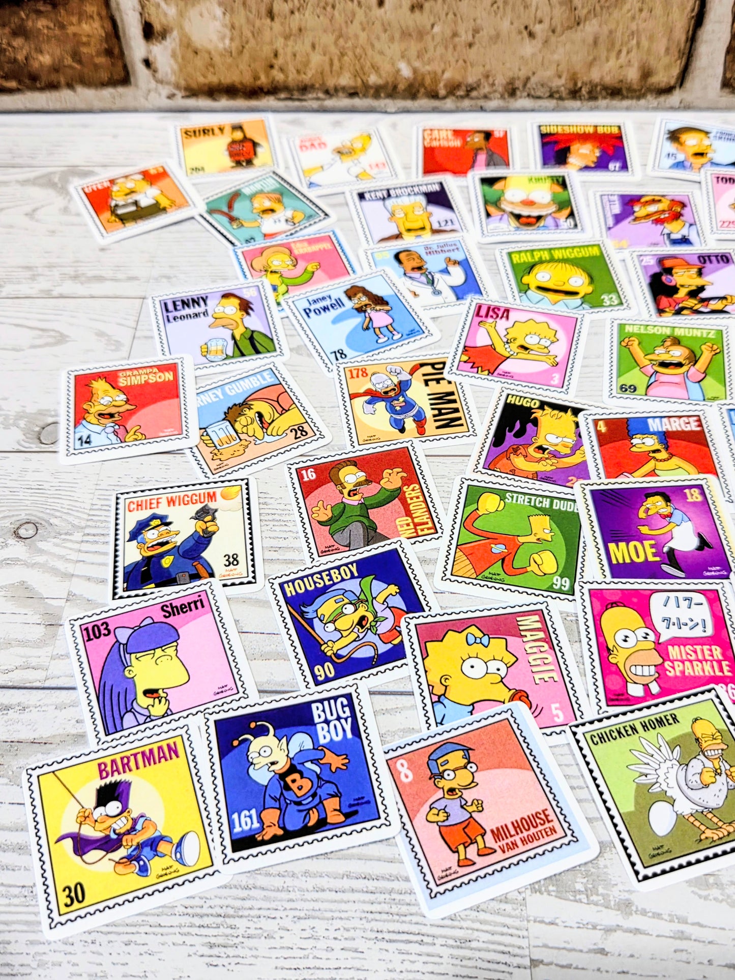 Assorted Simpsons postage-stamp style stickers spread out, featuring character portraits and icons