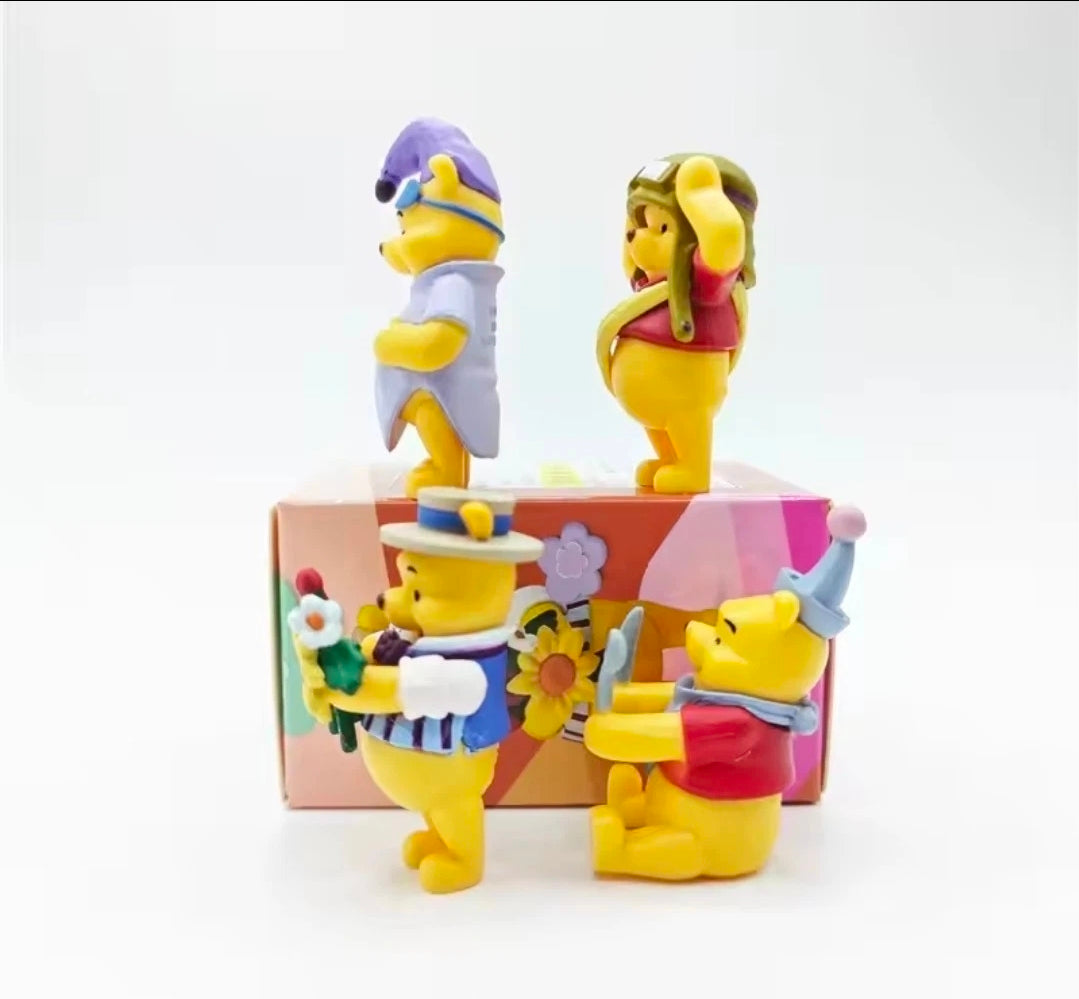 Winnie the Pooh character figures posed on display platform with colorful costumes