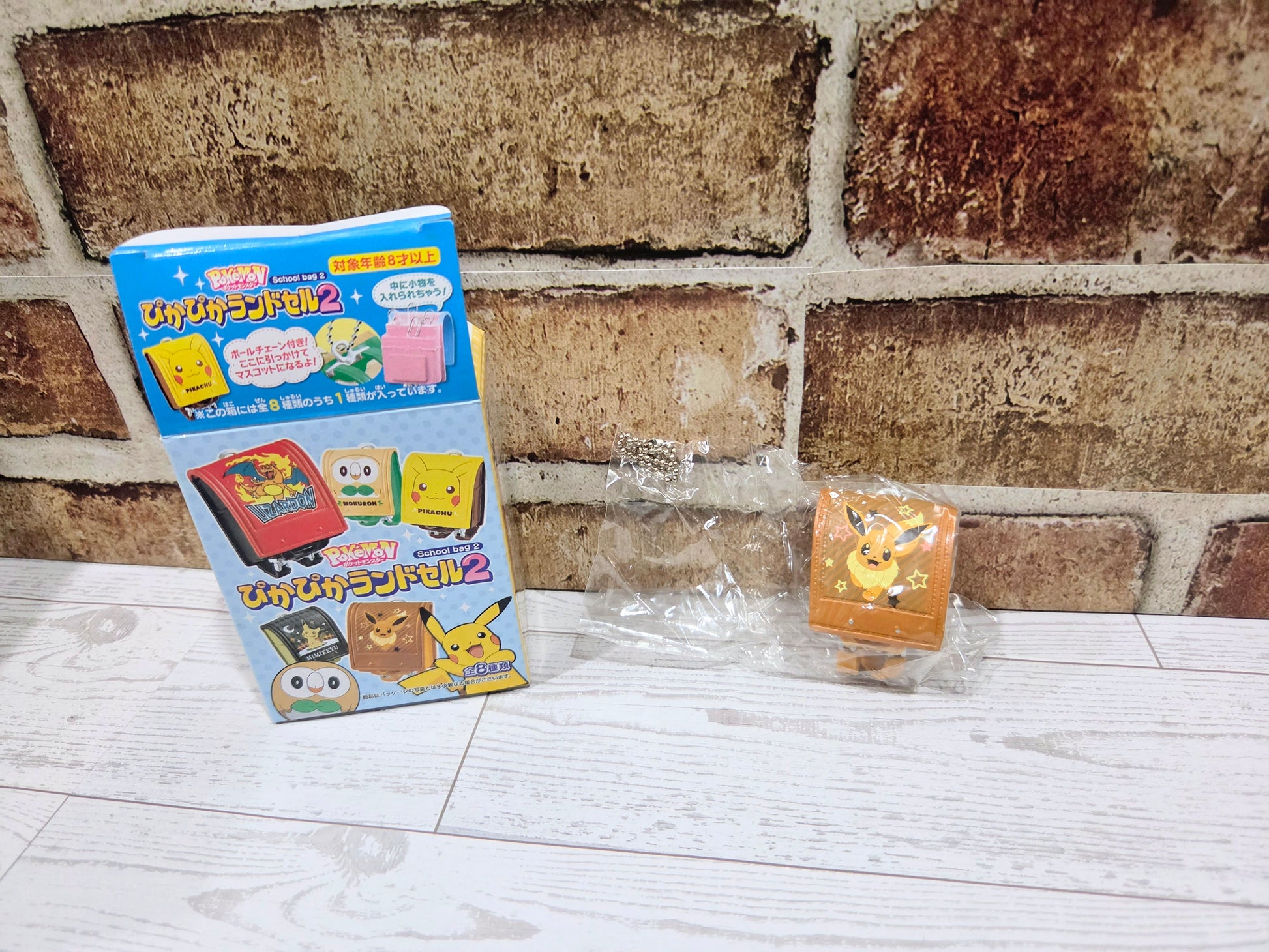 Orange mini school bag figure in clear wrapping, with Eevee-themed front panel
