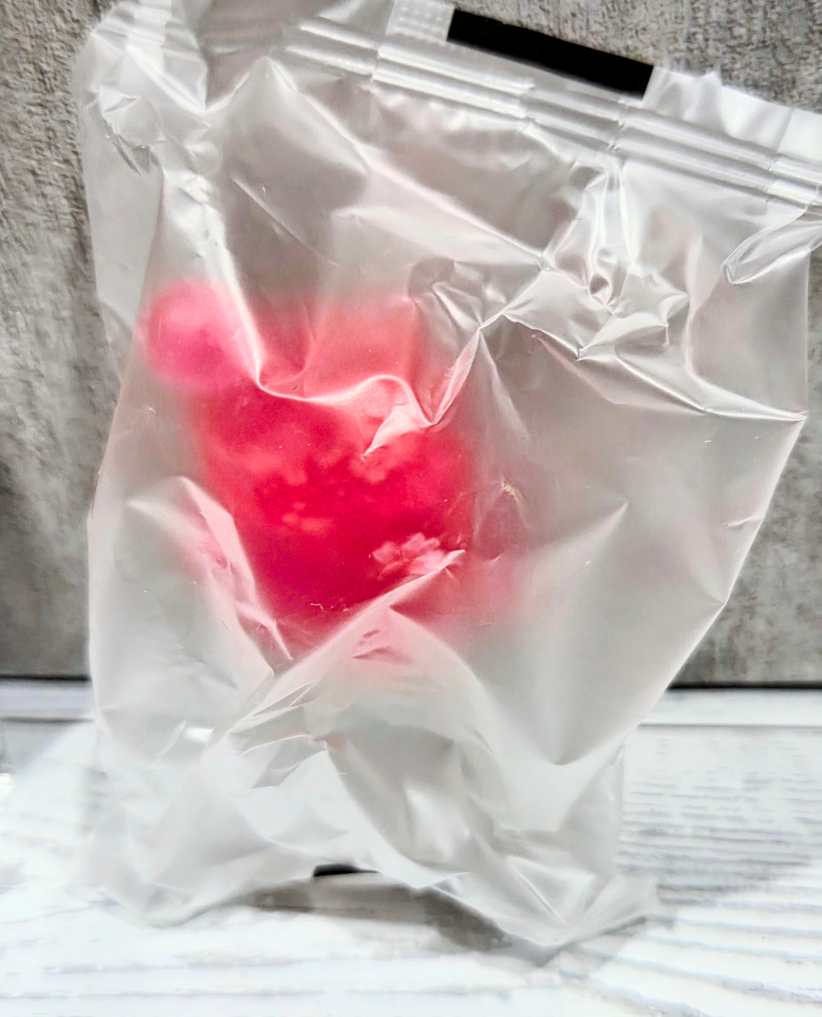 Clear plastic bag with translucent pink and red collectible figure inside