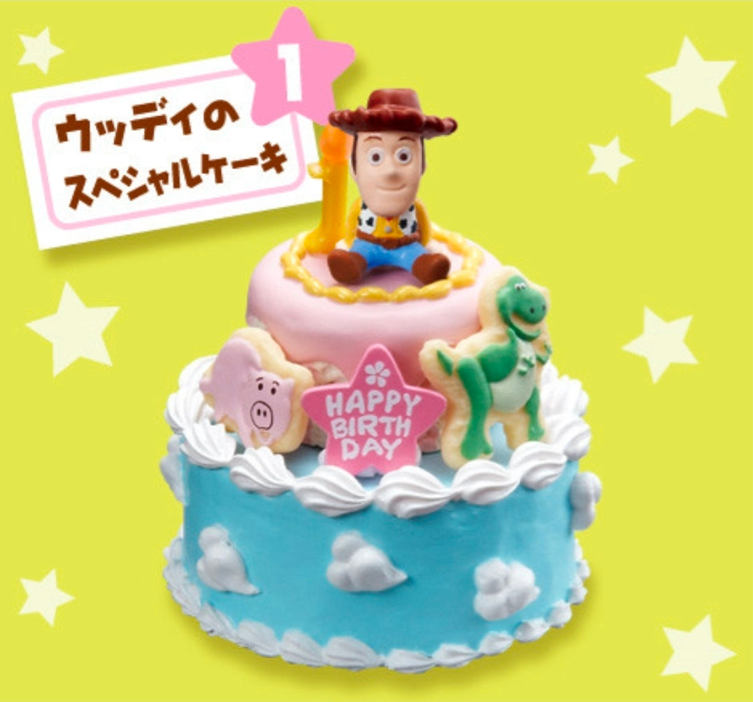 Mini birthday cake toy with Woody figure, pink top panel, “Happy Birthday” label and fondant details