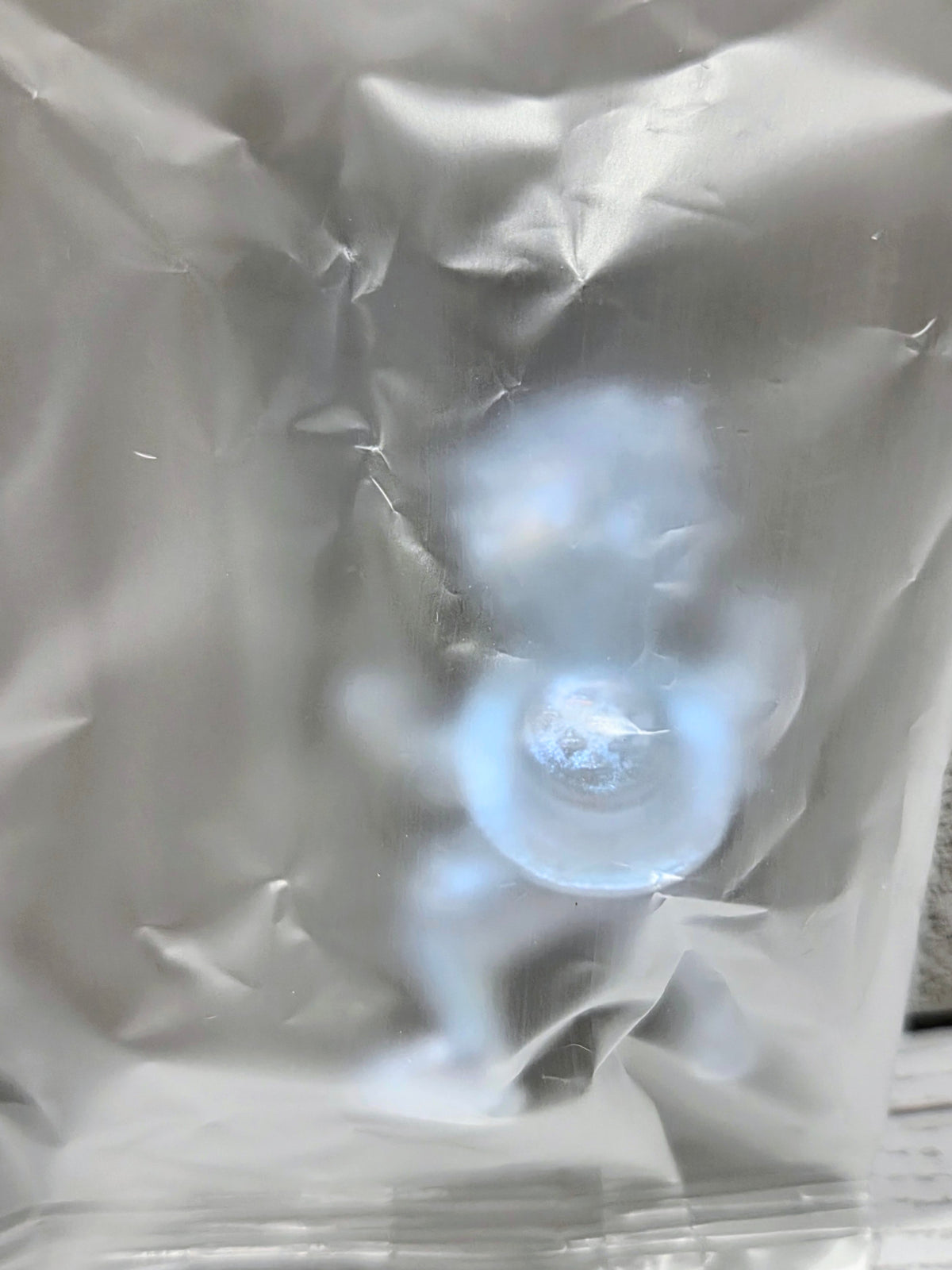 Clear plastic bag showing a pale blue shimmer mini figure inside