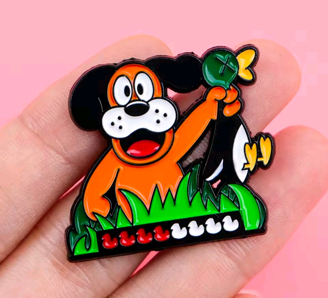 Colorful enamel lapel pin of orange cartoon dog standing in green grass.