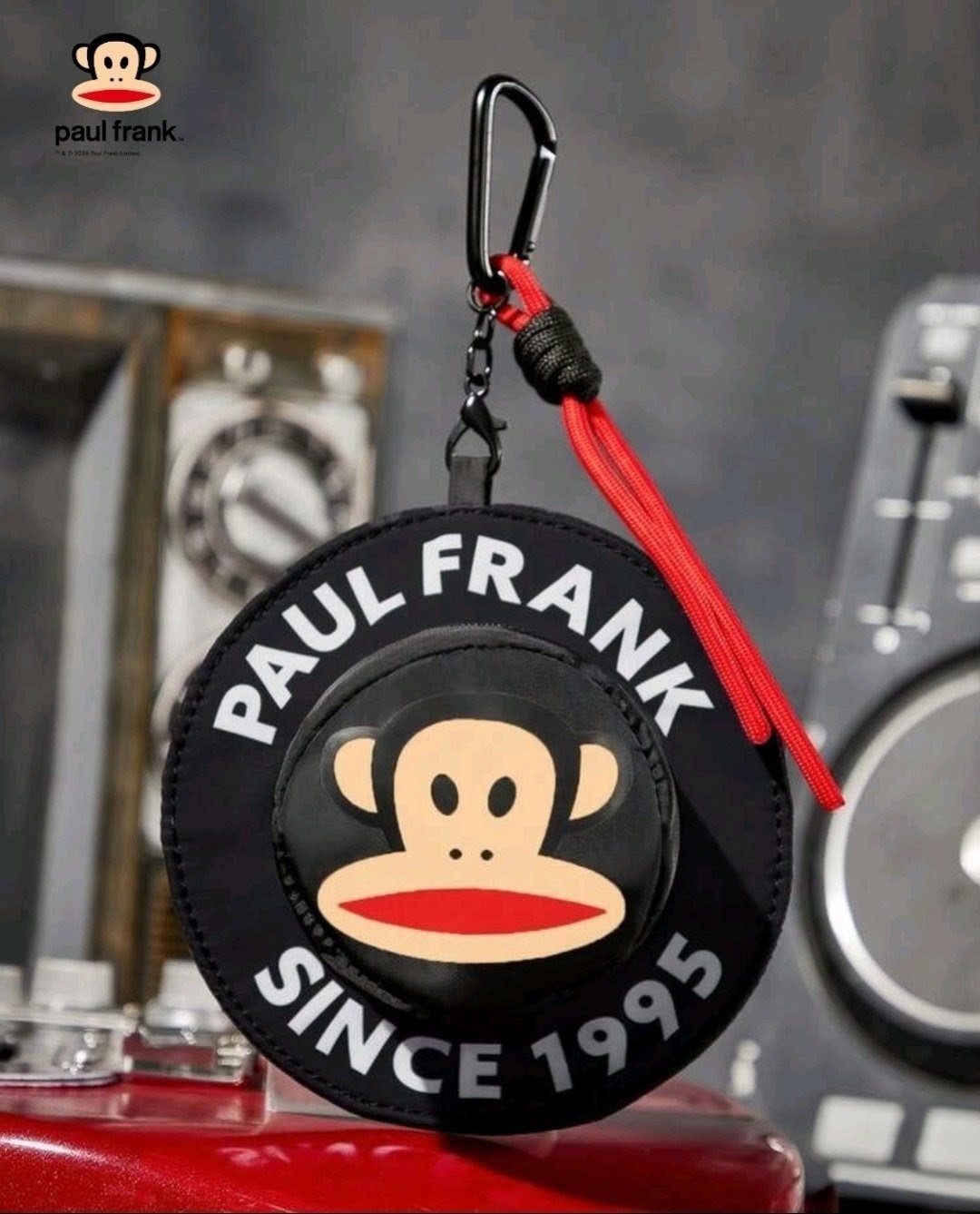 Round black monkey-face coin pouch with zipper, red tassel, and carabiner clip