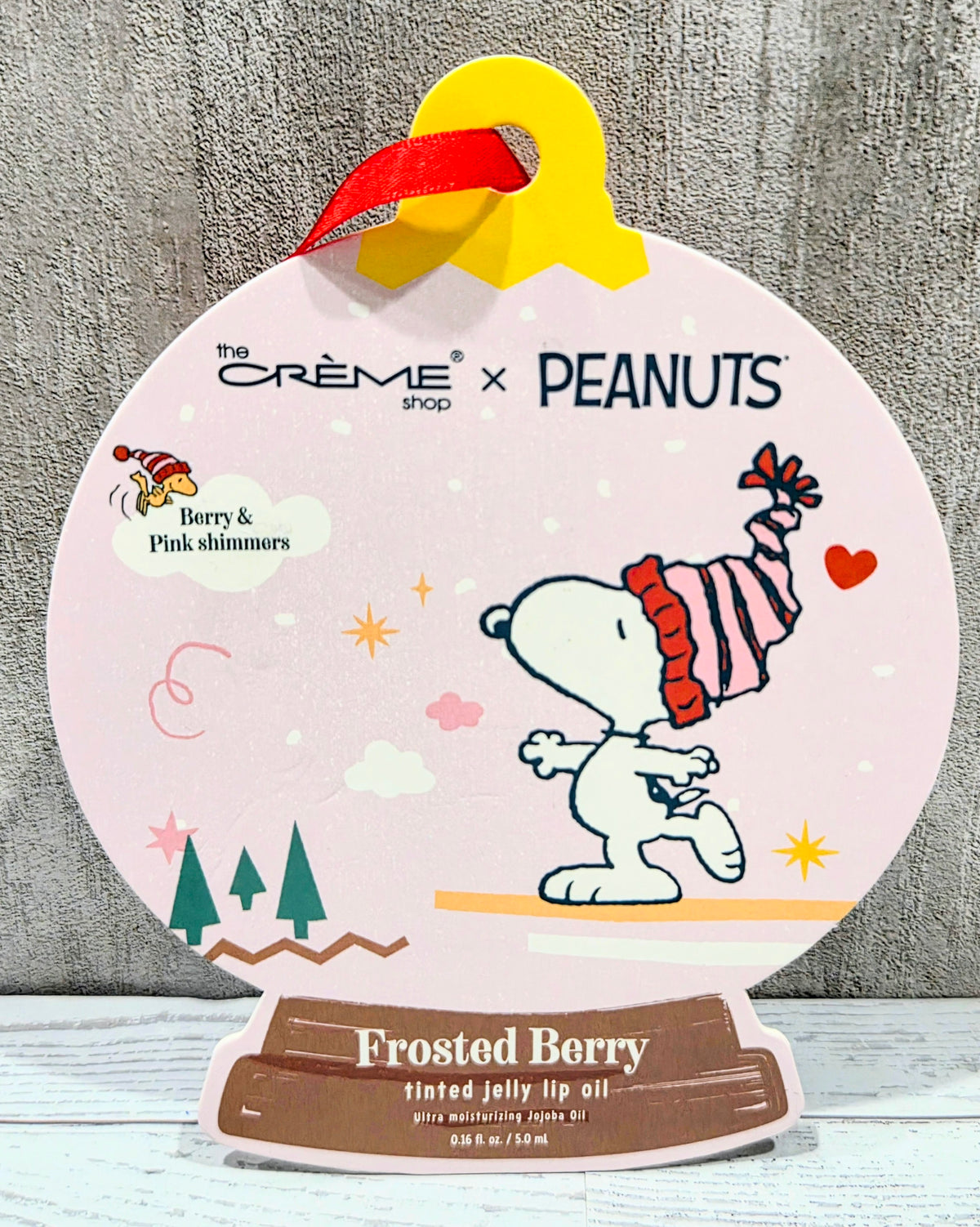 Tinted jelly lip oil box with Snoopy artwork and Frosted Berry label at bottom