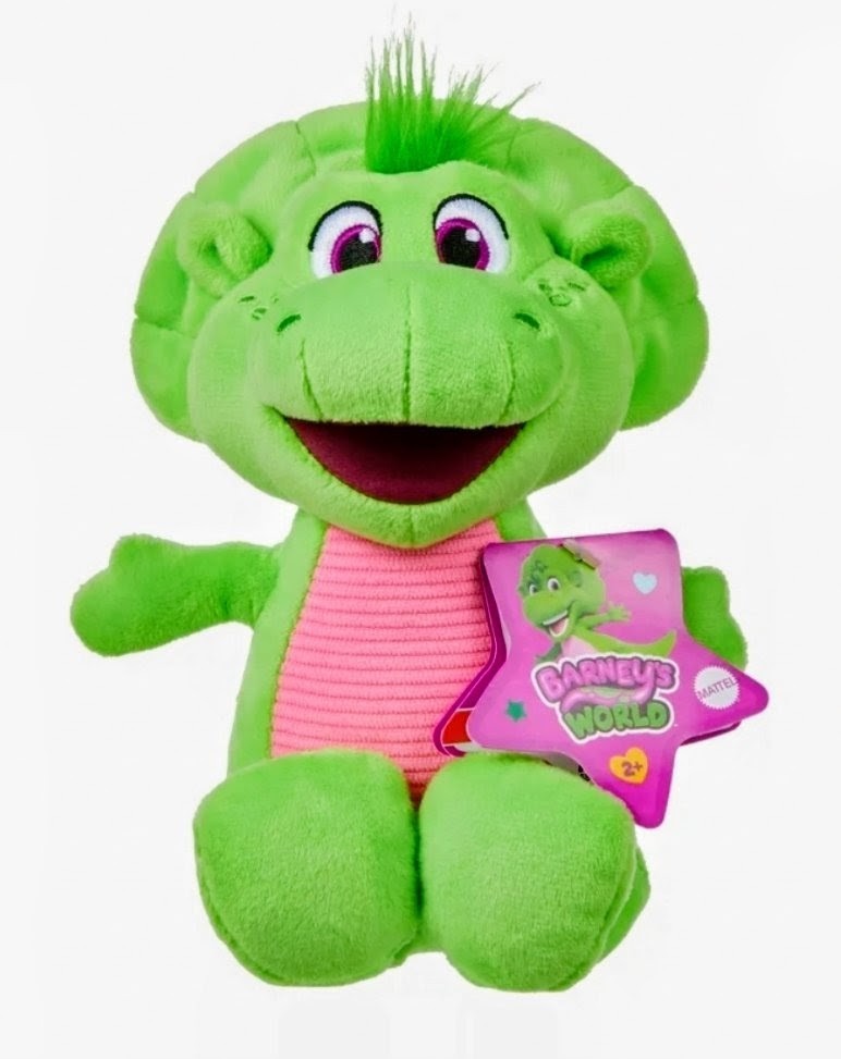 Green plush dinosaur character holding a purple book-style tag, pink striped shirt, smiling