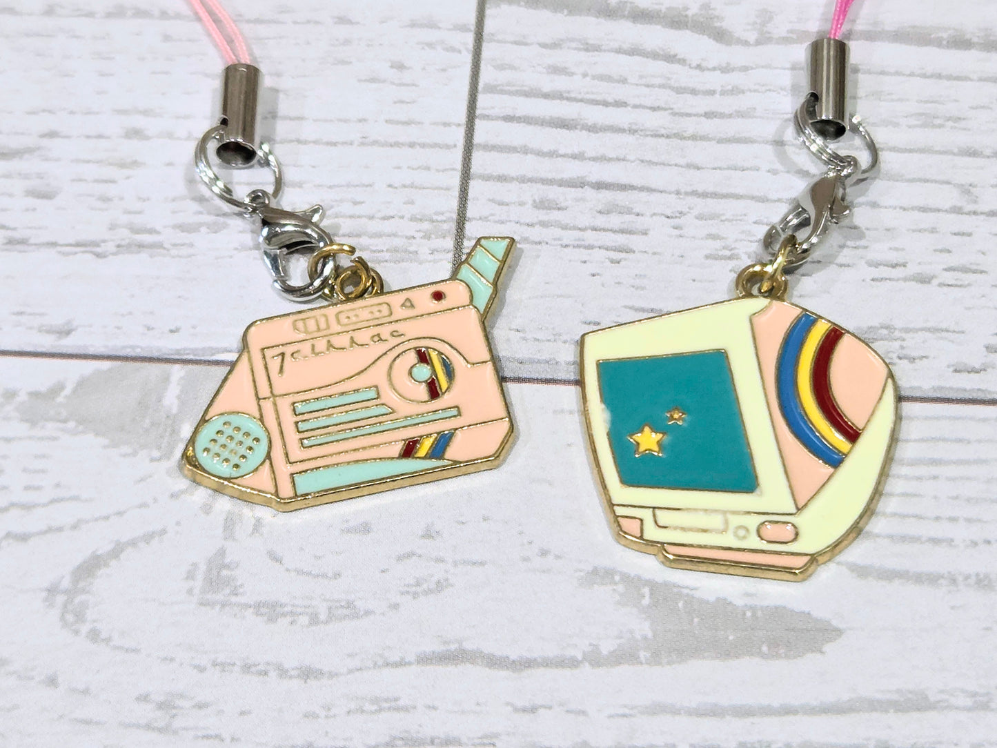 Two retro phone charms on silver clips with pink lanyard cords and teal screens
