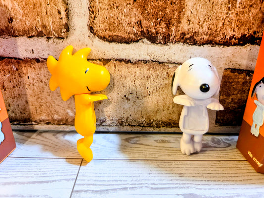 Pair of mini vinyl character figures: yellow and white standing on light wood floor
