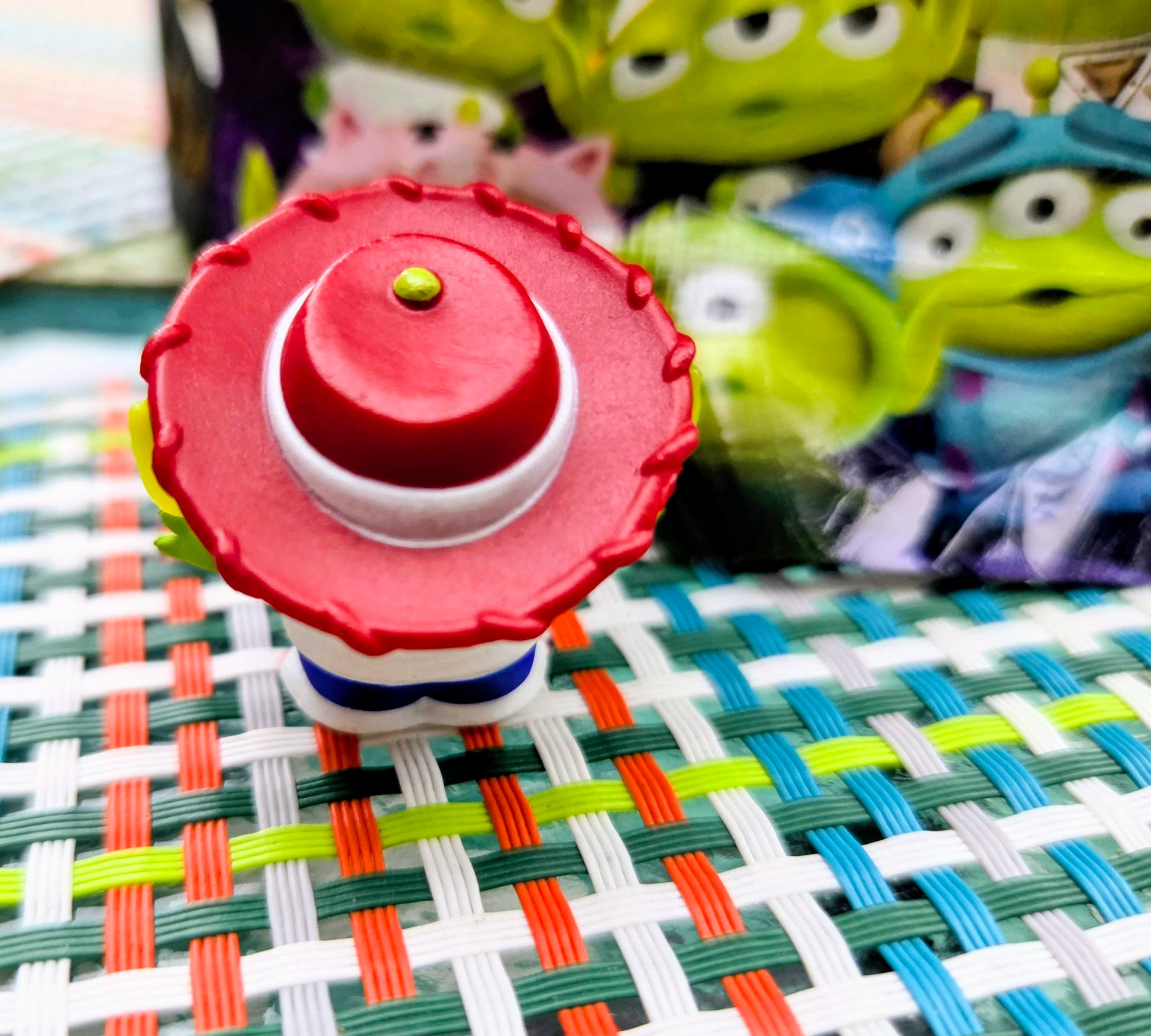 Green alien mini figure with red pizza-slice hat, white shirt, and blue belt, front view