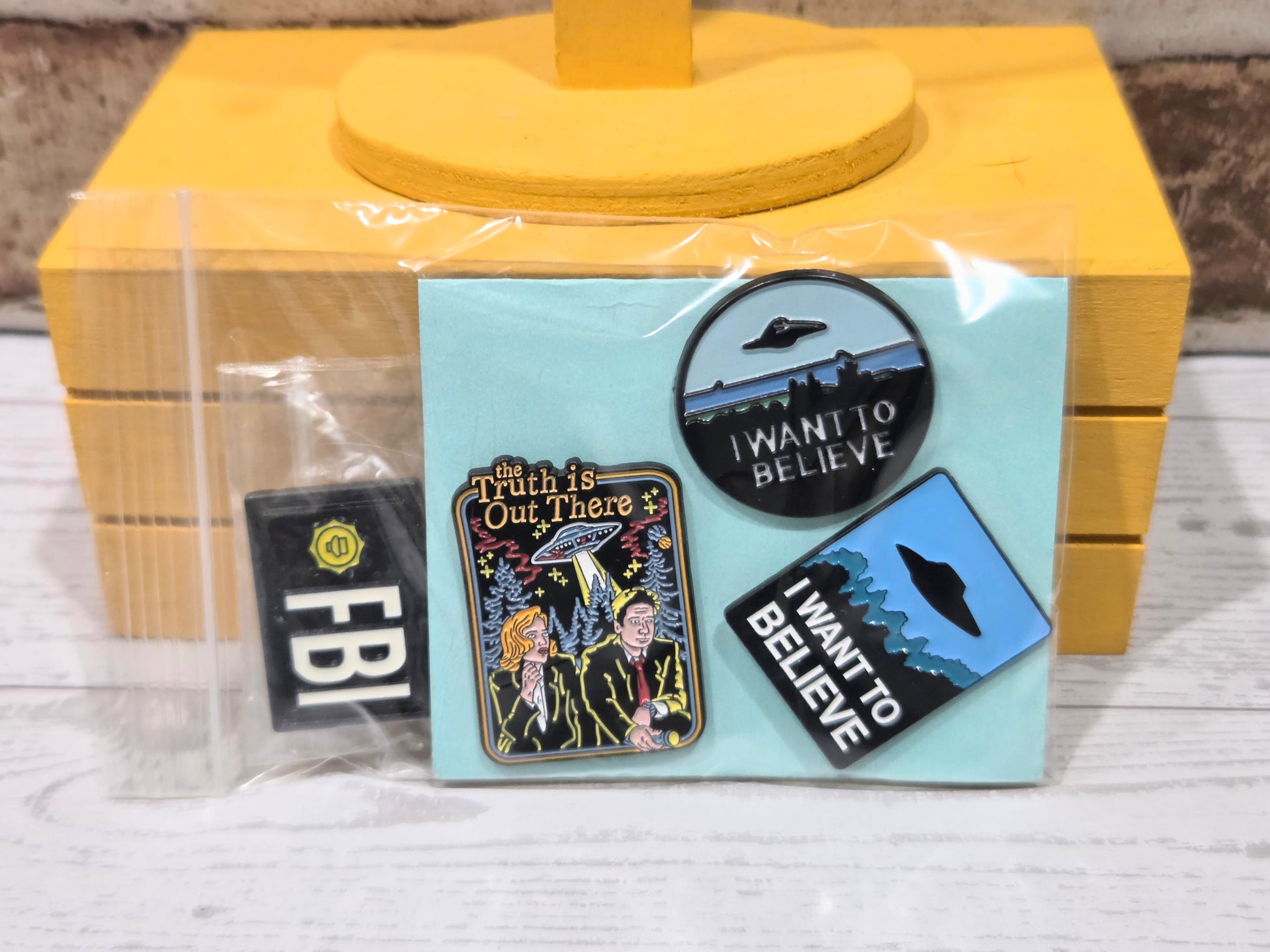 Enamel pin set in clear packaging on light blue card with multiple character designs.