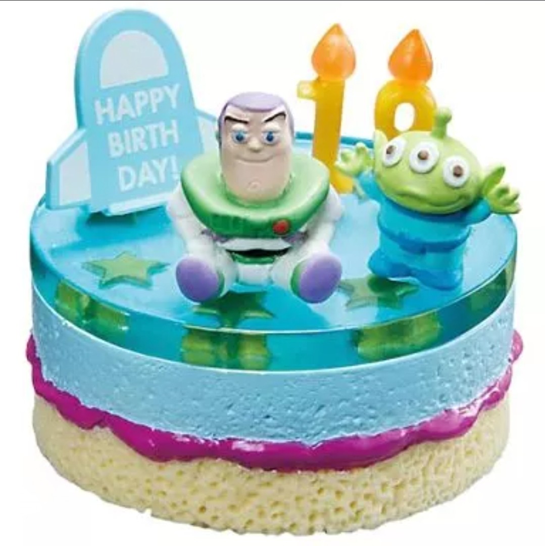 Close-up mini cake figure with Buzz, green alien, and two orange candles