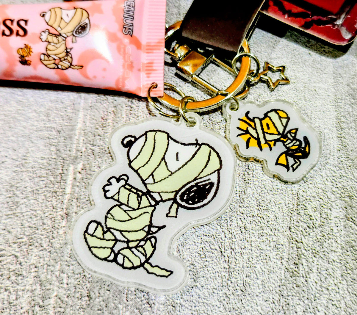 Keychain charm set featuring Snoopy stickers over Halloween lip gloss packs