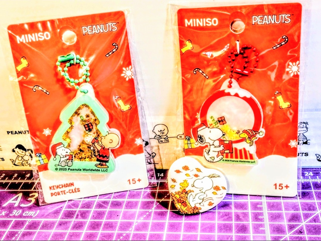 Two Miniso Peanuts Christmas keychain packs with Snoopy charms on red backing