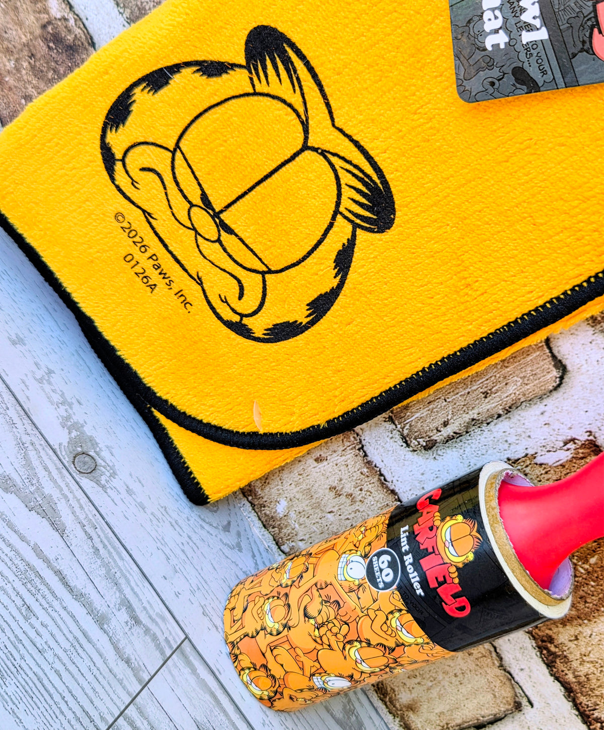 Yellow Garfield pet pouch with cartoon cat face and black zipper trim.