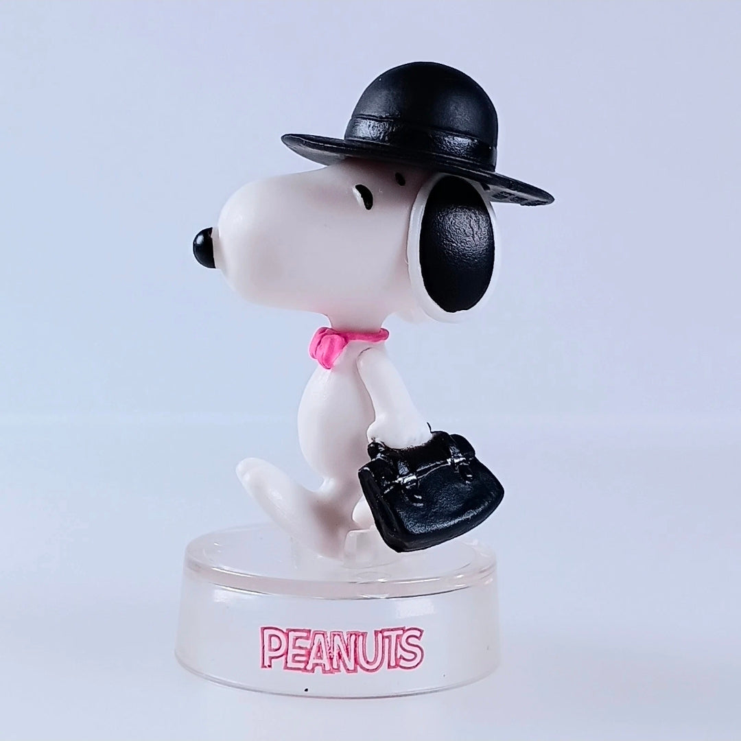 Snoopy figure wearing black hat and black bag, pink bow tie, clear PEANUTS base