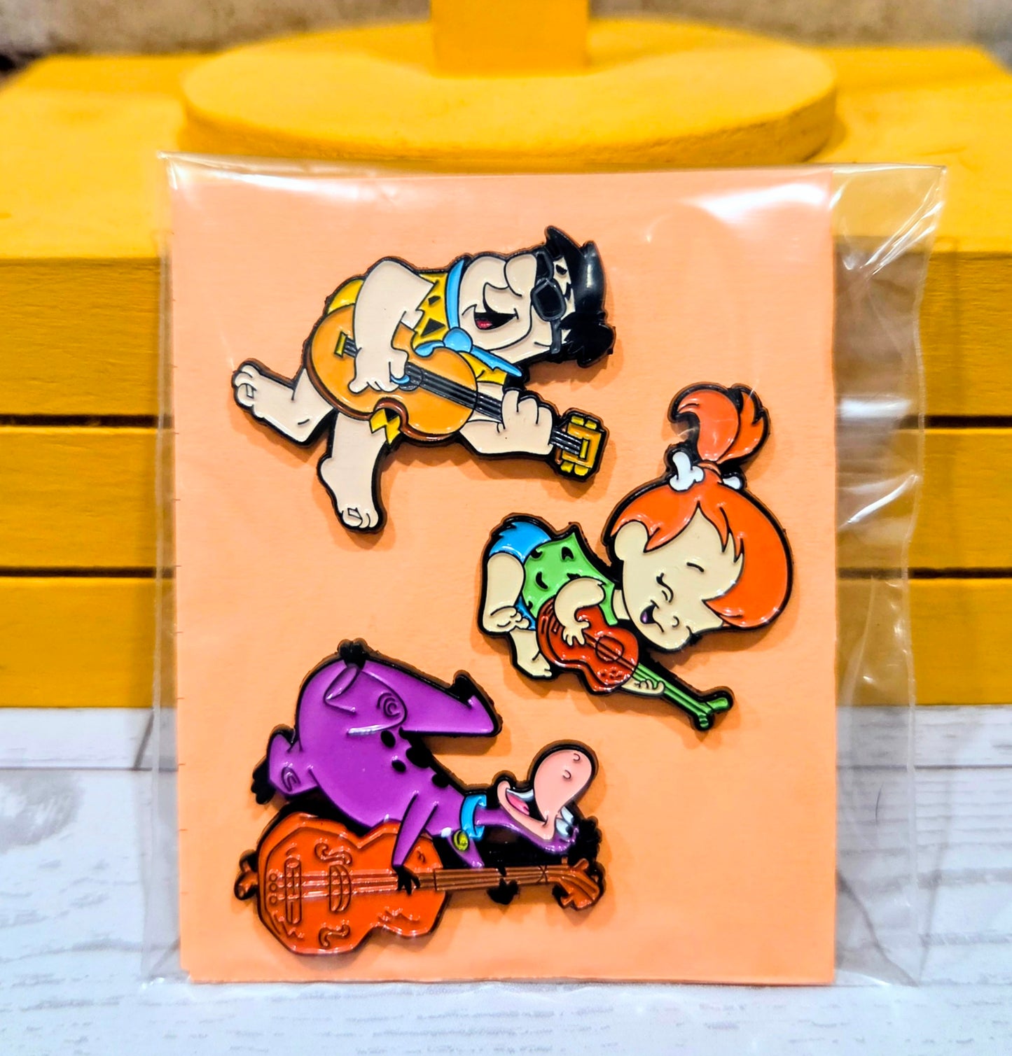 Enamel pin set in clear sleeve with Fred, Pebbles, and Dino characters