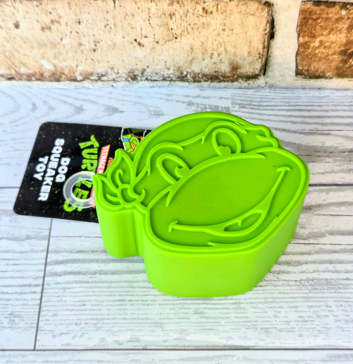 Neon green lint roller brush case shaped like a turtle with hang tag