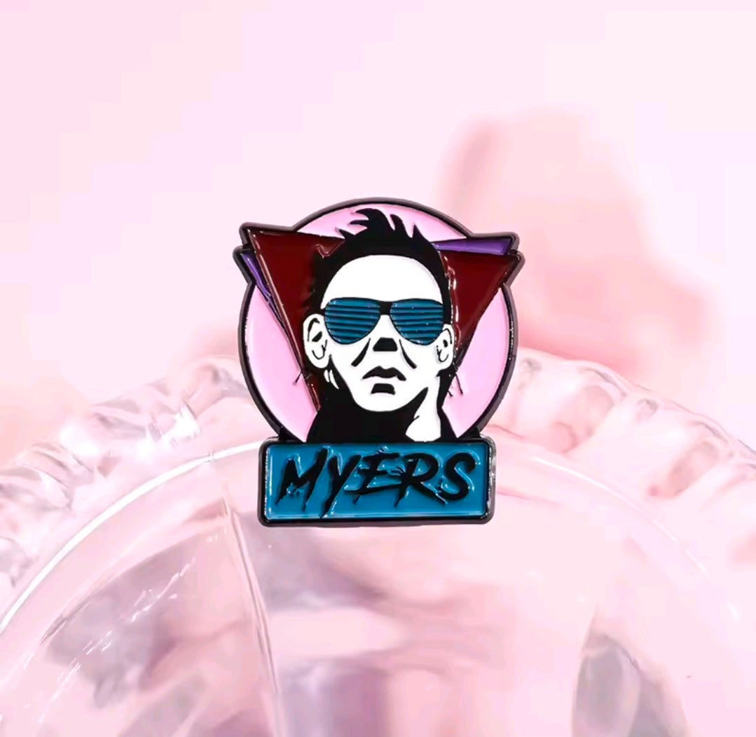 Enamel pin featuring Michael Myers with blue sunglasses and dark bat-shaped frame