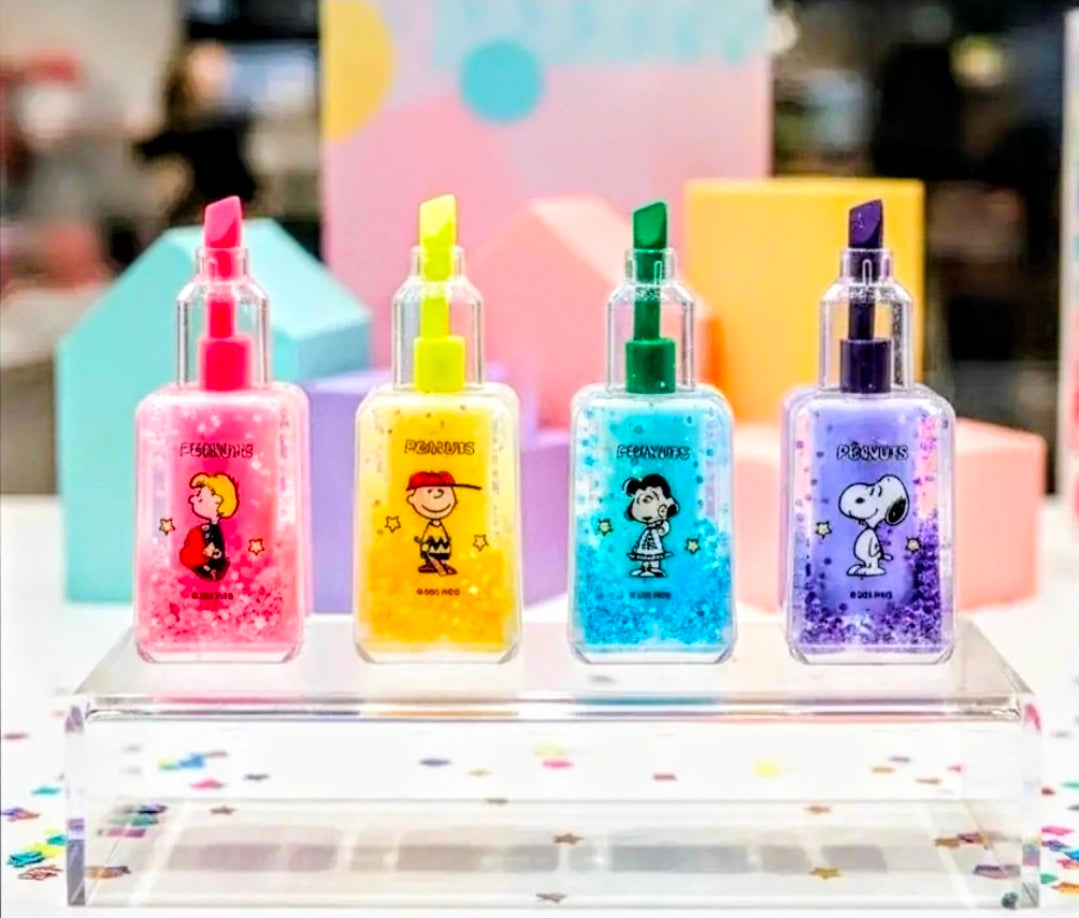 Peanuts glitter highlighter bottles with bright caps—pink, yellow, green, and purple.