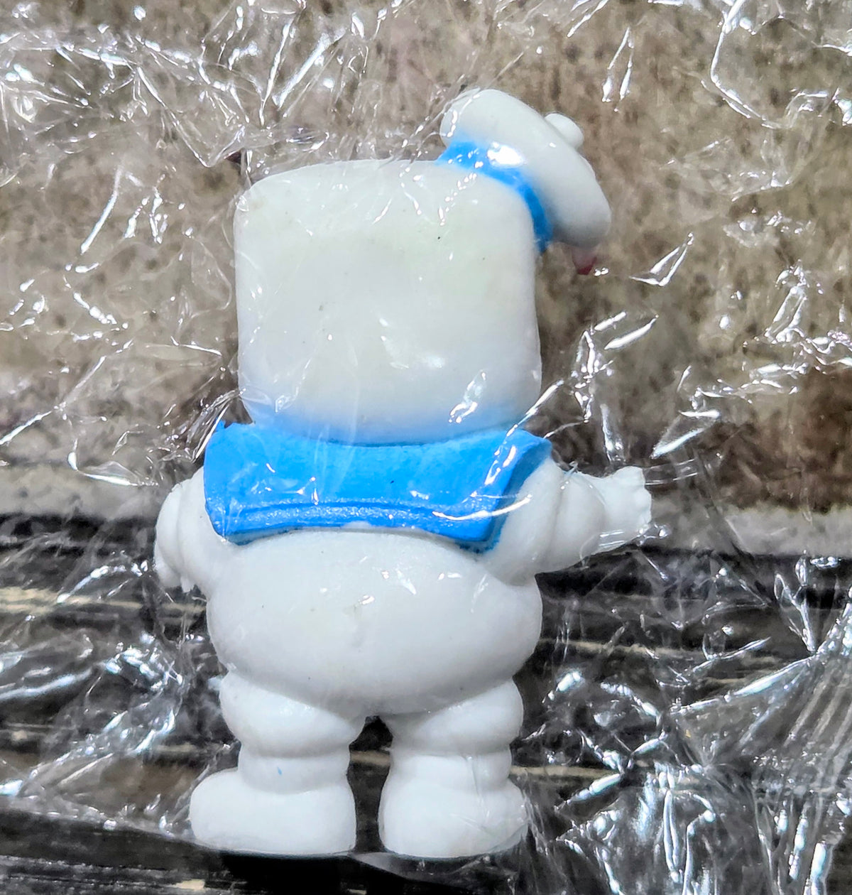 White mini figure back view, blue collar and trim, wrapped in clear plastic