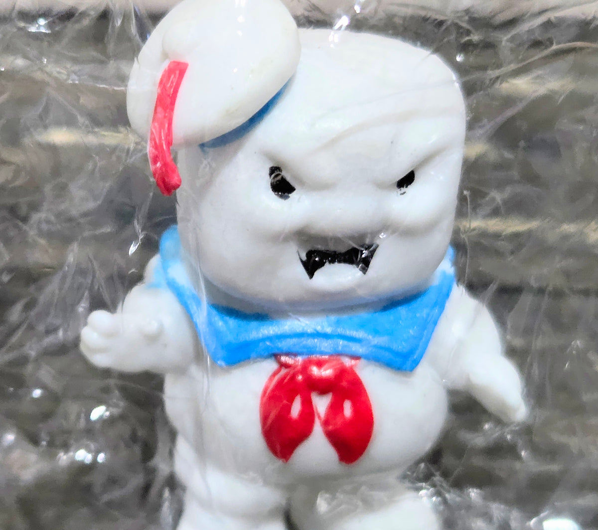 White mini figure front close-up, red hat, blue bib, red chest emblem