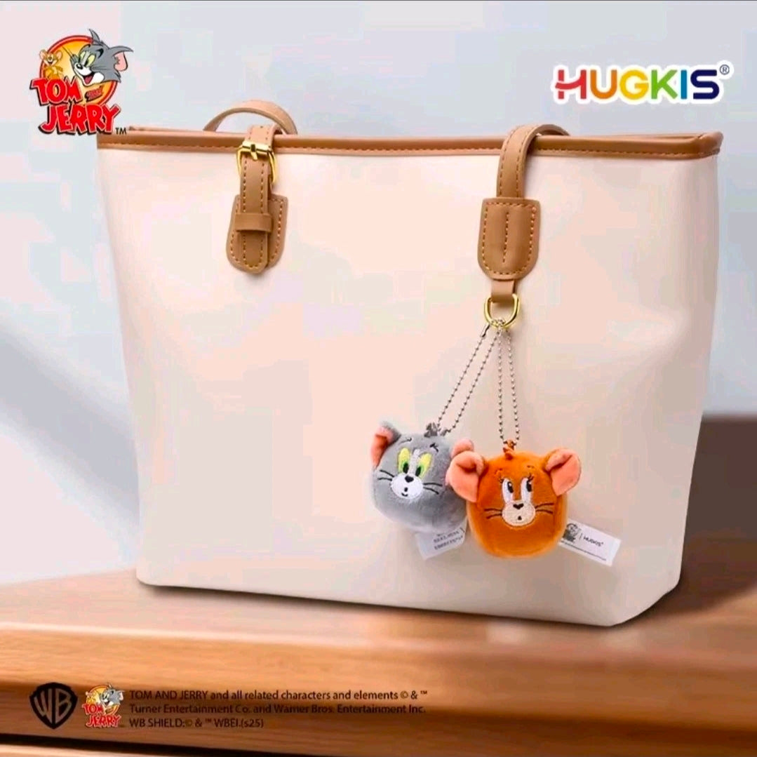 Mini plush keychain duo hanging from tan straps on a white bag